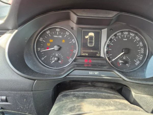 The ŠKODA OCTAVIA 1.2 BENZIN/TNG dashboard displays illuminated check engine and oil warning lights. Visible are the speedometer, tachometer, fuel gauge, and a central display with a top-down image of the car.
